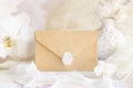 Sealed envelope near white orchid flowers and decor close up, pastel romantic wedding mockup