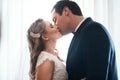 Sealed with a kiss. an affectionate young couple standing indoors together and kissing after their wedding.