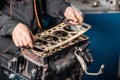 Sealing gasket in hand. The mechanic disassemble block engine vehicle. Engine on a repair stand with piston and Royalty Free Stock Photo