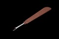 Seam ripper with brown plastic handle on black background