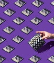 Seamless checkerboard pattern on a monochrome purple background. Female hand is holding chess board tilted to the right. Black and