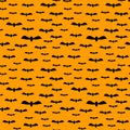 Seamless cute Halloween pattern with small and big flying black bats on orange background. Holiday print for fabric textile Royalty Free Stock Photo