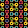 Seamless pattern of donuts multi colored on a black isolated background. Confectionery sweets top view.