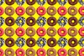 Pattern of pink and chocolate donuts on bright yellow background top view tasty doughnuts backdrop colorful sweet dessert Royalty Free Stock Photo