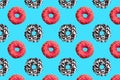Pattern of pink, white and chocolate donuts on blue background top view, tasty doughnuts backdrop, colorful sweet dessert Royalty Free Stock Photo