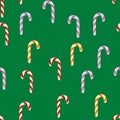 Seamless pattern with striped Christmas candy on the green background. Cartoon style.