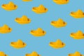 Seamless pattern of yellow plastic childrens boats on a light blue background