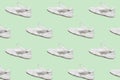 Seamless regular pattern of light colored casual sneakers on a mint background.