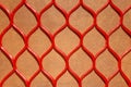 Seamless texture of a red plastic mesh with abstract repeating patterns in the form of rombs on brown background