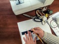 Seamstress draws a pattern with a pencil and a ruler on a white sheet of paper against the sewing supplies. Top view on a brown Royalty Free Stock Photo