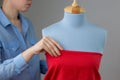 Seamstress measuring beautiful fabric on blue tailor dummy in her workshop. Royalty Free Stock Photo