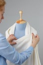 Seamstress measuring beautiful fabric on blue tailor dummy in her workshop. Royalty Free Stock Photo