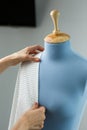 Seamstress measuring beautiful fabric on blue tailor dummy in her workshop. Royalty Free Stock Photo