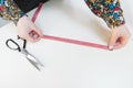 Seamstress measuring the length of cloth tape measure on a white background. Copyspace