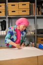 Seamstress with pink hair and colorfull clothes cutting sewing patterns.