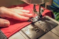 Seamstress sews clothes made of red cloth on a sewing machine Royalty Free Stock Photo