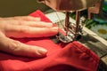 Seamstress sews clothes made of red cloth on a sewing machine Royalty Free Stock Photo
