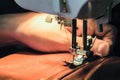 Seamstress sews clothes made of red cloth on a sewing machine. Work by the light of the built-in hardware lamp. Royalty Free Stock Photo