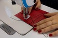 A seamstress sews clothes from red cloth on a sewing machine. Steel needle with looper and presser foot close-up Royalty Free Stock Photo