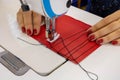 A seamstress sews clothes from red cloth on a sewing machine. Steel needle with looper and presser foot close-up Royalty Free Stock Photo