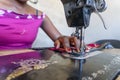 Seamstress using her black sewing machine to do African dresses