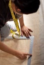 A seamstress is working measuring a piece of fabric