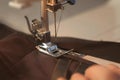 Seamstress is working sewing clothes in sewing machine, hands closeup.