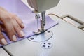 Seamstress works on a sewing machine. The girl sews and holds a lilac cloth Royalty Free Stock Photo