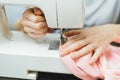 Seamstress works on a sewing machine. The girl sews and holds a pink cloth Royalty Free Stock Photo