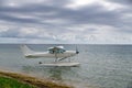 Seaplane anchored near shore on cloudy day. White floatplane on calm wwaters under dramatic sky. Single-engine Royalty Free Stock Photo