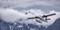 Seaplane Flying over the Rocky Mountains covered in snow and clouds. Royalty Free Stock Photo