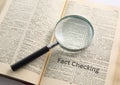 Magnifying Glass on Dictionary with \'Fact Checking\' Royalty Free Stock Photo