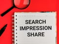 Search impression share written on note book with a pen and magnifying glass. Royalty Free Stock Photo