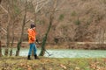 Search With A Metal Detector. A young woman in an orange jacket is looking for lost artifacts along the river. Hobbies and