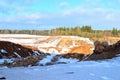 View from the mountain to the red sand in the snow of a small canyon.