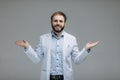 In search of right medical solution. Handsome young doctor in white uniform stretching out his arms while standing against grey Royalty Free Stock Photo