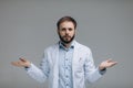 In search of right medical solution. Handsome young doctor in white uniform stretching out his arms while standing against grey Royalty Free Stock Photo