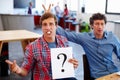 Searching for answers. Portrait of two coworkers looking confused while holding a question mark sign. Royalty Free Stock Photo