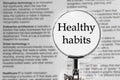 Healthy habits in magnifying glass on text background
