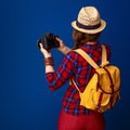 Tourist woman on blue background with DSLR camera taking photo Royalty Free Stock Photo