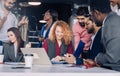 Young multi-ethnic work team exchanges ideas gathering around laptop computers