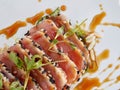 Seared ahi tuna slices on a bed of seaweed salad sprinkled with sesame seeds and oil and garnished with sprouts