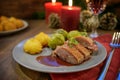 Seared duck breast with duchess potatoes and brussels sprout served with red wine sauce as a festive christmas dinner with candles