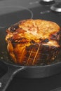 Searing a glazed gammon ham joint of meat.  cast iron frying pan on a hob stove Royalty Free Stock Photo