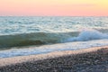 Beach at sunset, small waves in the sea, sea foam and spray, as a background Royalty Free Stock Photo