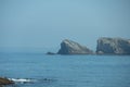 seascape with a beach and rocky islets in the background on a sunny day with fog on the horizon Royalty Free Stock Photo