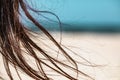 Seascape, beach and woman`s hair. Girl and her long naughty hair on the strong wind.