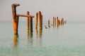 Seascape with blue calm water and rows of Rusty pipes with green algae on summer day. Rusty pipes remaining from old pier. Royalty Free Stock Photo