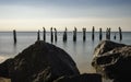 Seascape with cormorants resting on pilings of ruined piers on rocky jetty