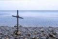Seascape with cross of sticks on rocky beach in overcast day. Royalty Free Stock Photo